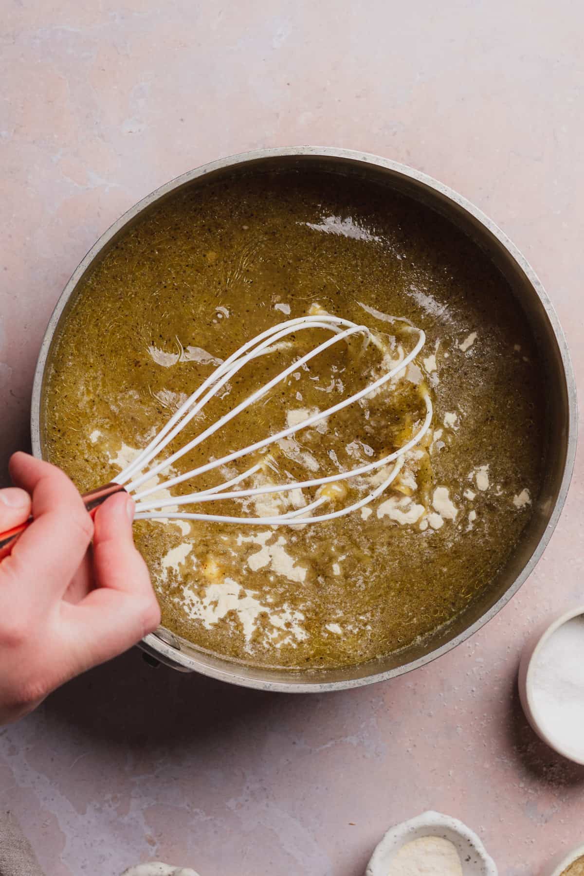 hand whisking xanthan gum in a pot to make chicken gravy. 