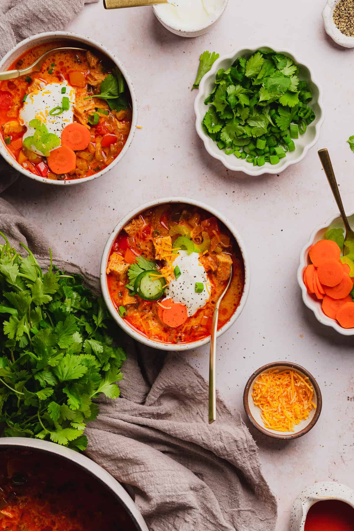yummy bowls of buffalo chicken chili with lots of fresh veggies for toppings, sour cream, and cheese