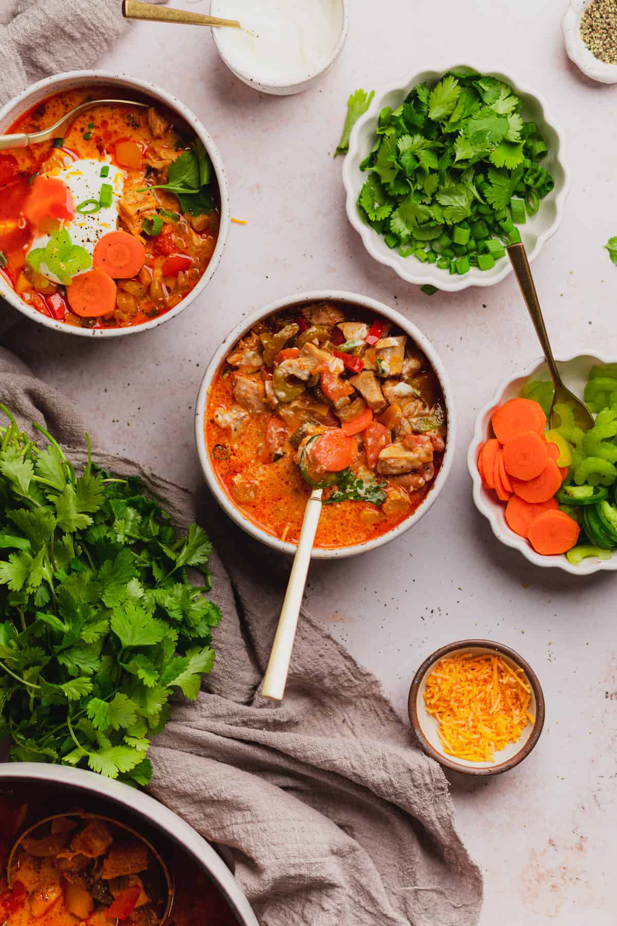 stirring buffalo chicken chili with sour cream and loads of fresh herbs and toppings 