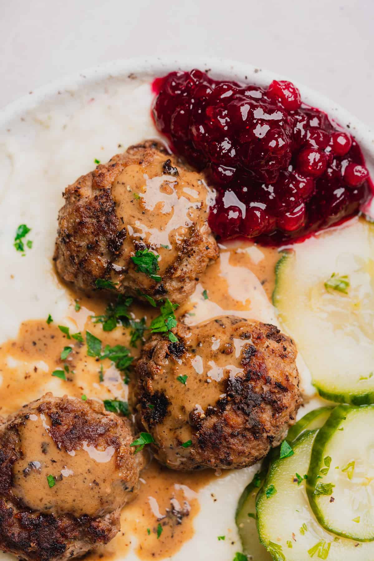 close up shot of keto swedish meatballs with lingonberries and cucumbers