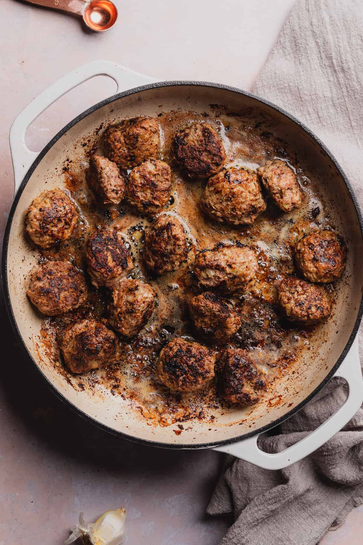 browning swedish meatballs in an enameled cast iron skillet