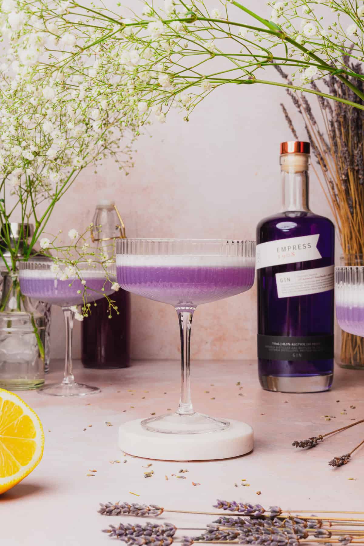 lavender cocktail with a nice foamy egg white rim and a bottle of empress gin beside it 