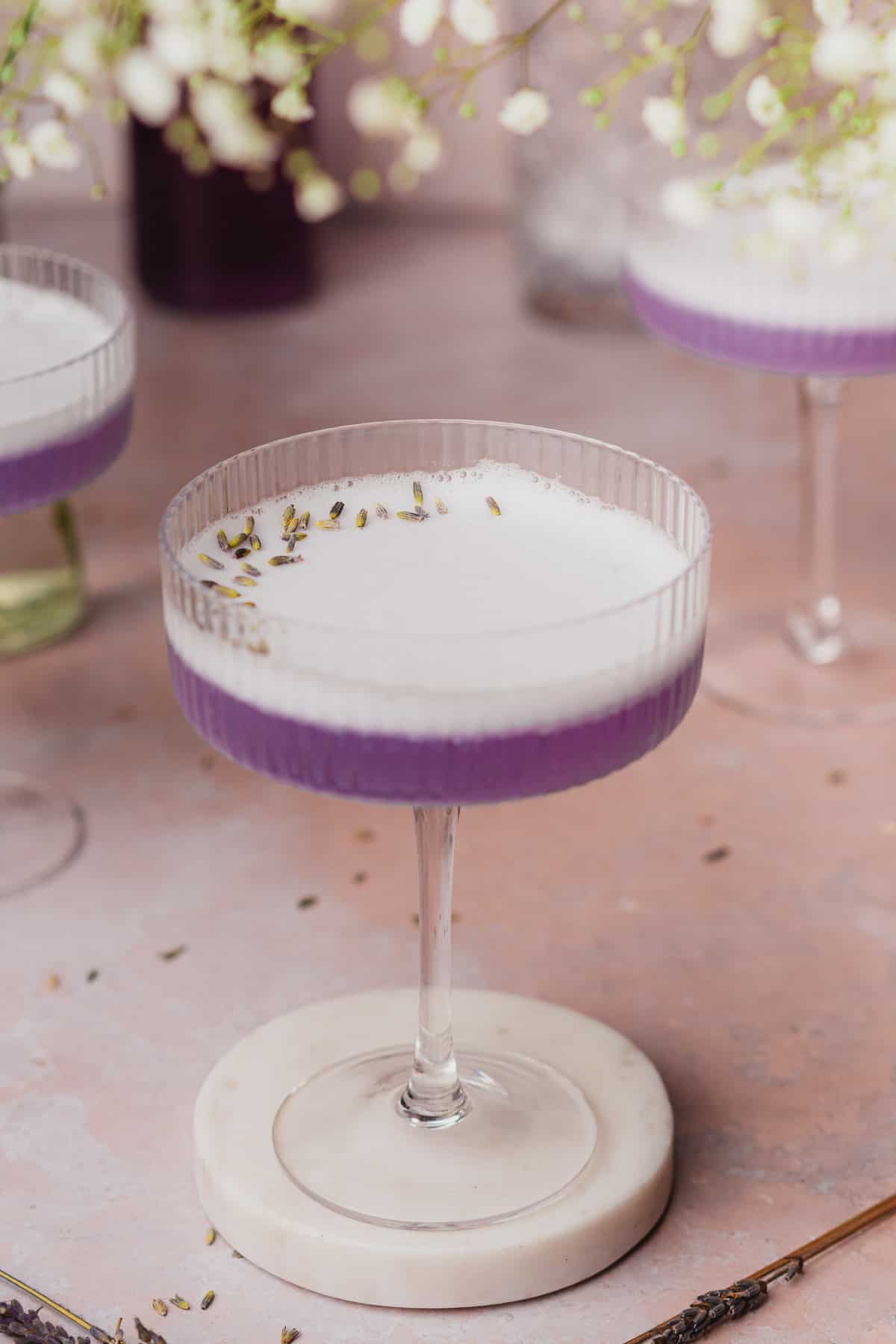 beautiful lavender gin cocktail with foamy egg white topping and dried lavender buds 