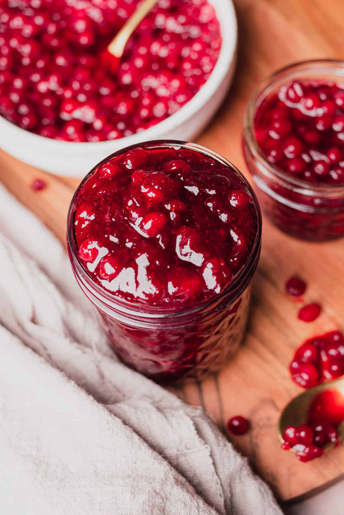 lingonberry sauce recipe with various jars filled with lingonberry sauce on a wooden board. 