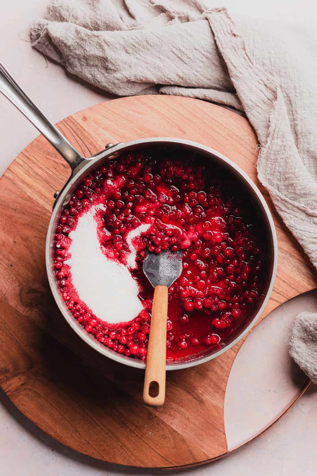 lingonberry sauce in a pot with sweetener, and a rubber spatula stirring it in.