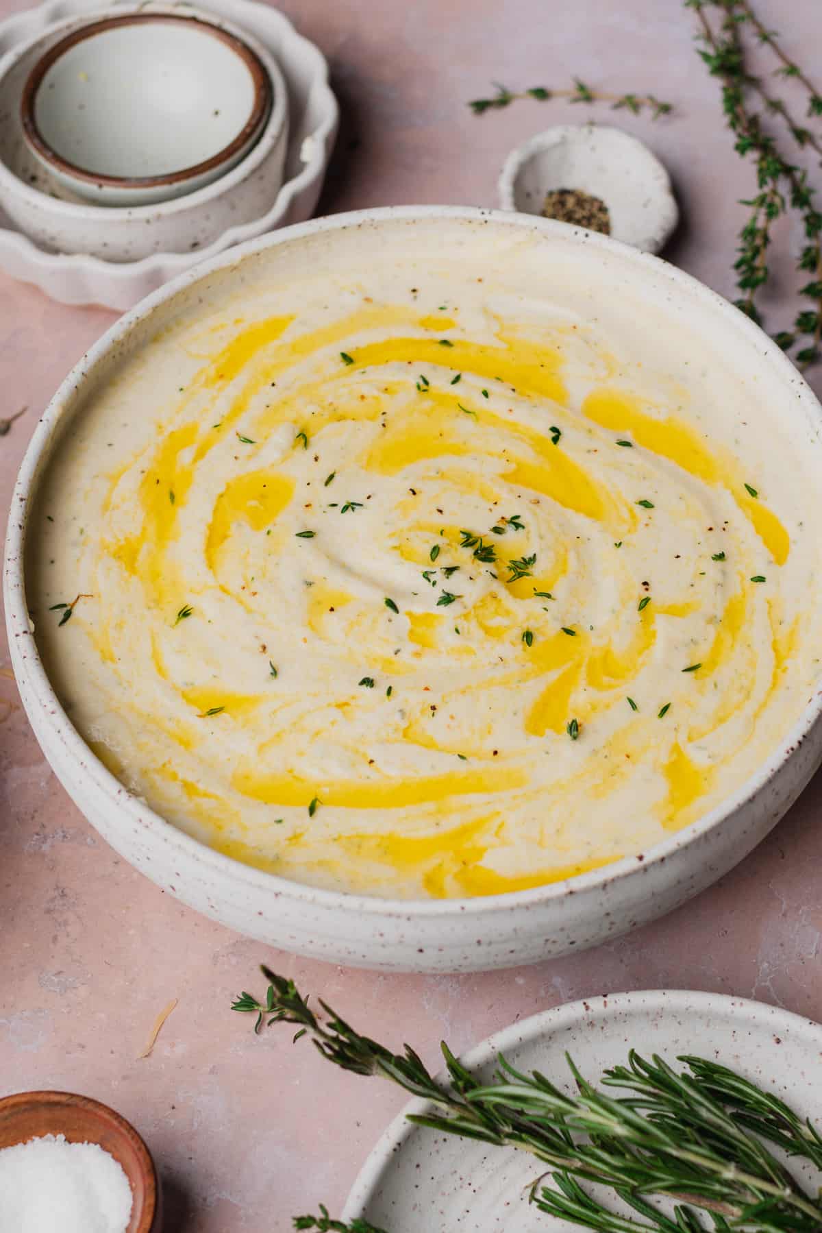 large bowl of creamy mashed turnips topped with melted butter swirls and fresh thyme.
