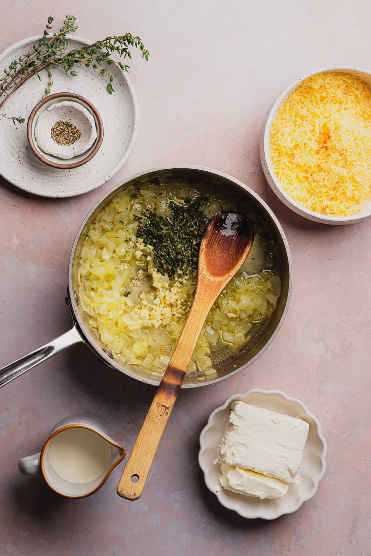 cooking onions, herbs, and garlic in a sauce pan and stirring with a wooden spoon.