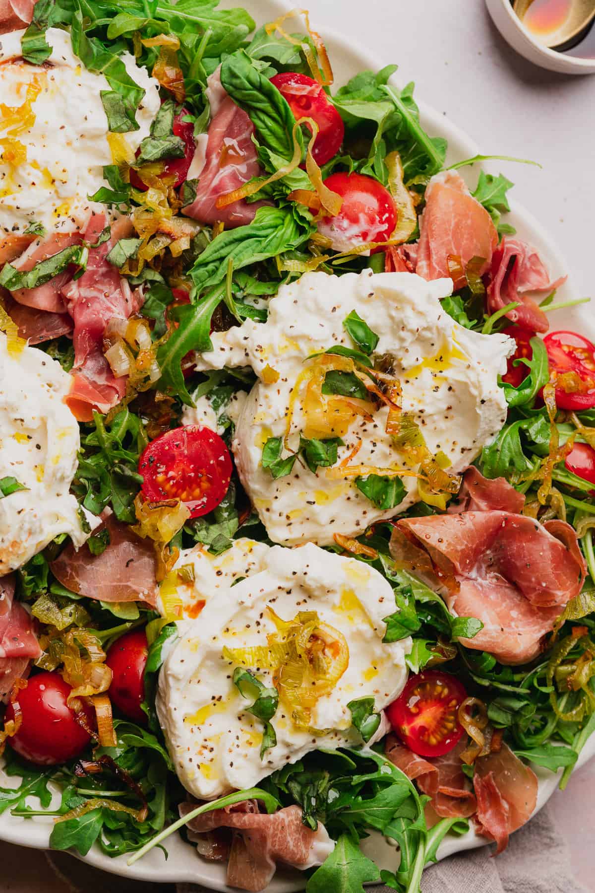 burrata balls on an arugula salad with prosciutto, tomatoes, leeks and basil. 