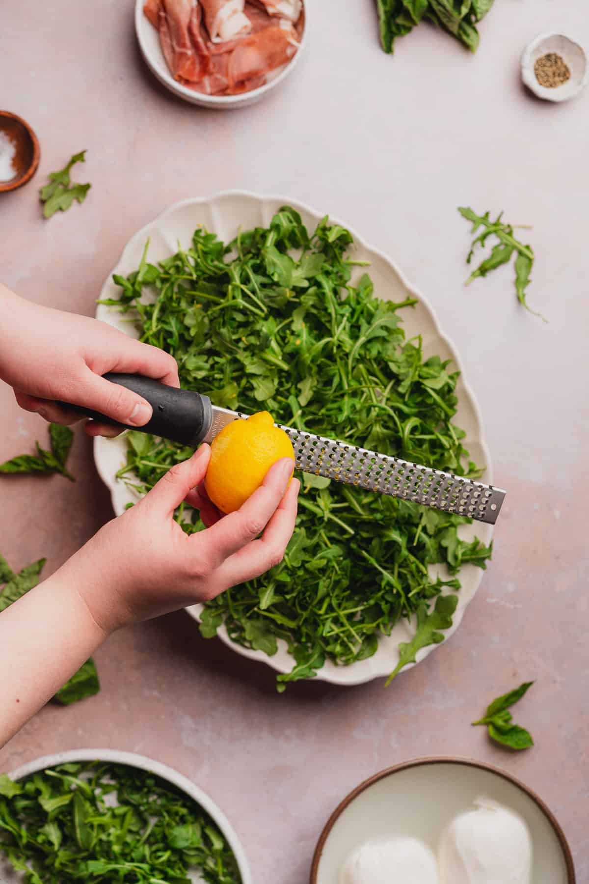 zesting lemon over top of arugula