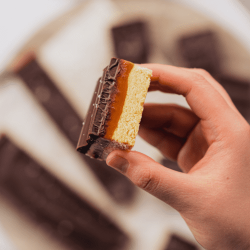 Gluten Free Caramel Slice held in a hand from a top down view
