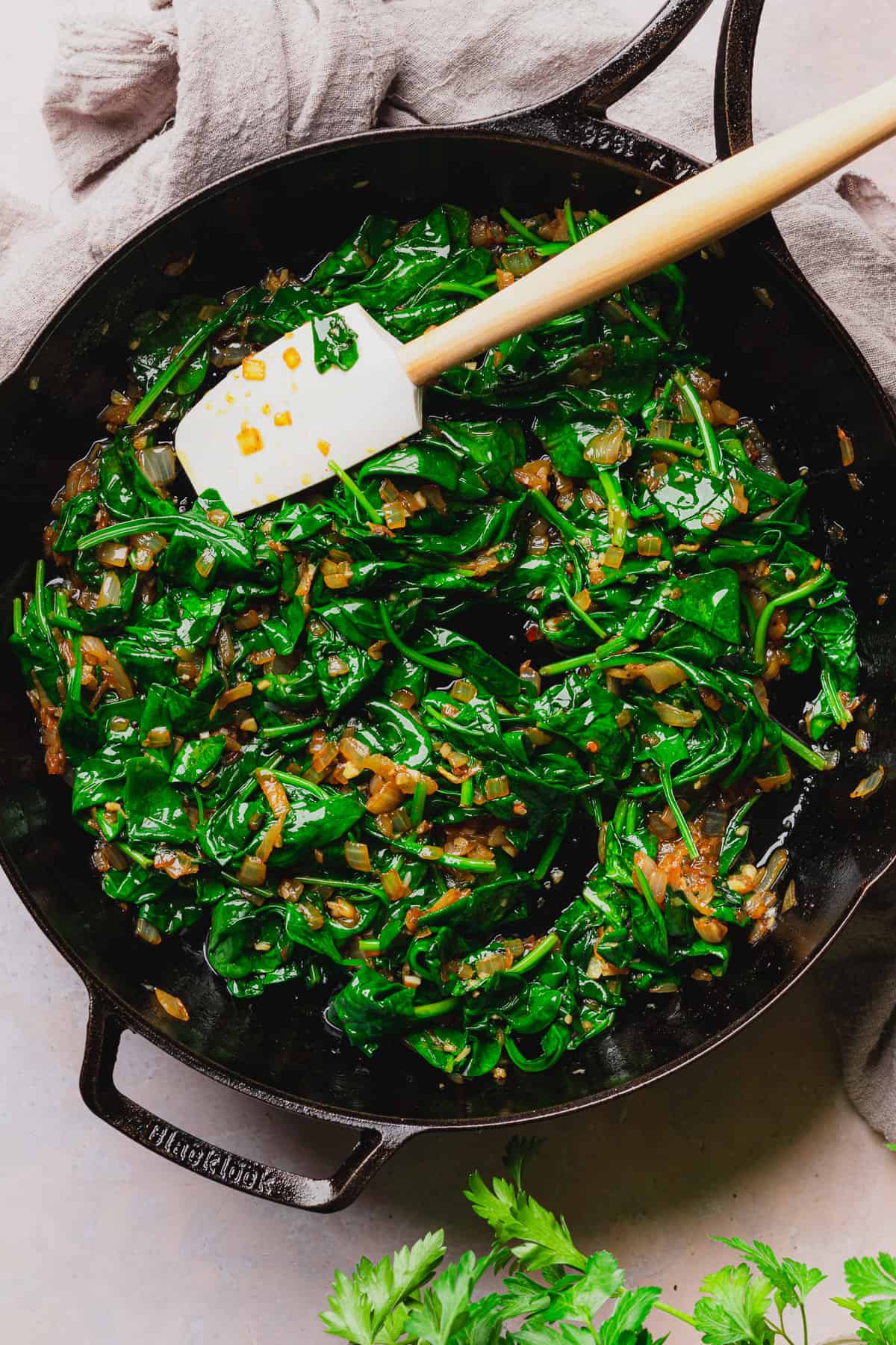 wilted spinach in a cast iron skillet with onions and garlic. 
