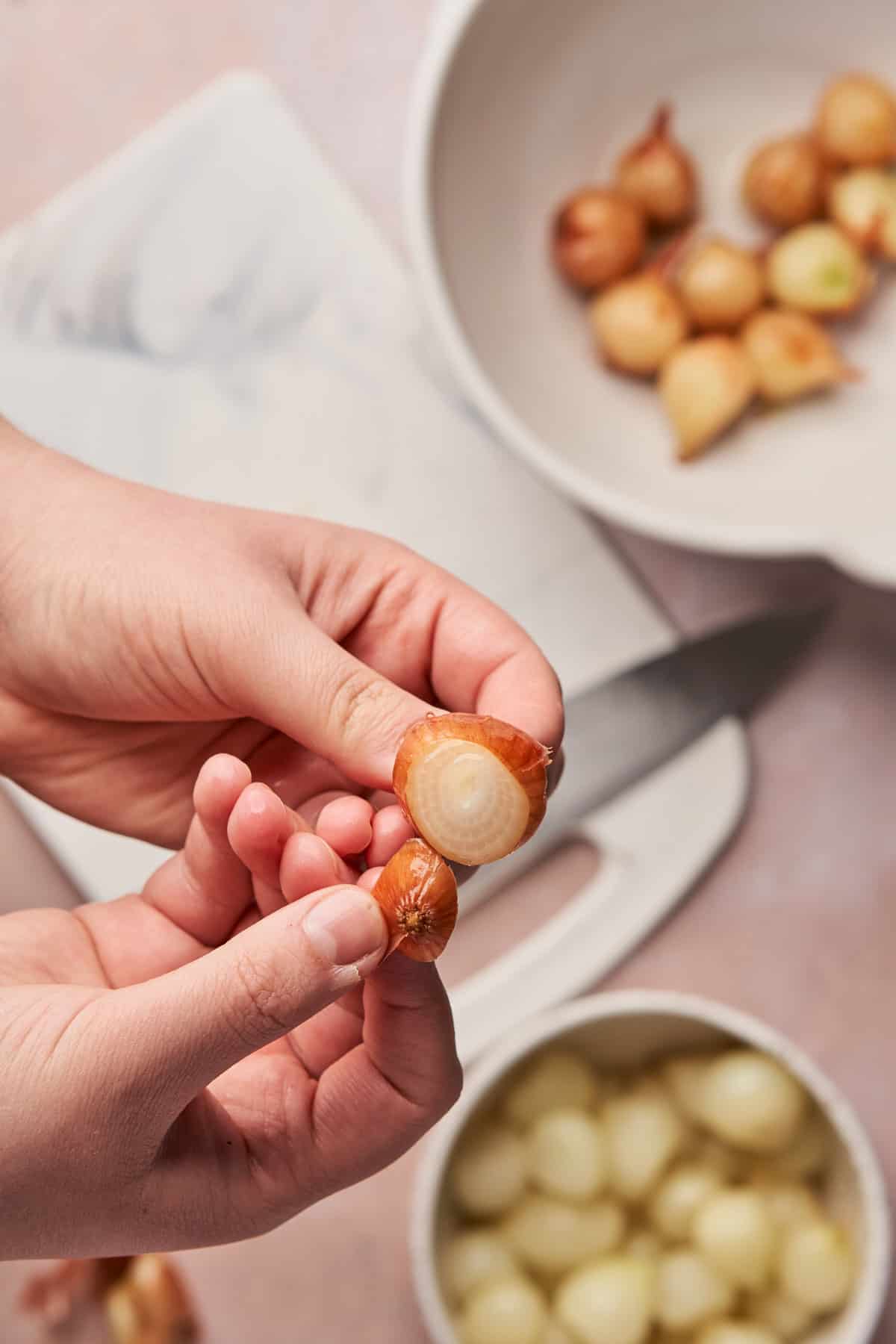 hand pushing the pearl onion through to remove the skin.