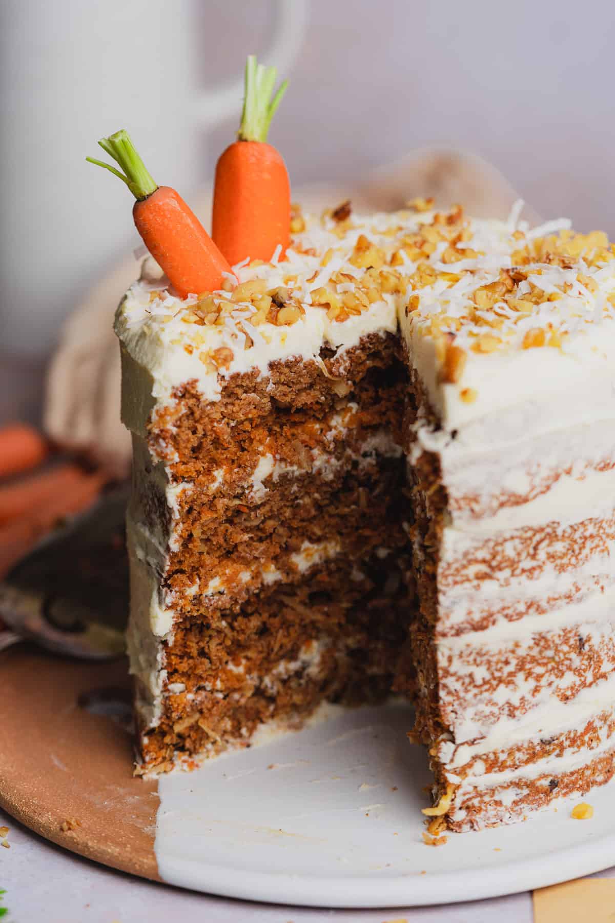 shot of a keto carrot cake topped with walnuts and real carrots poking out of the top.