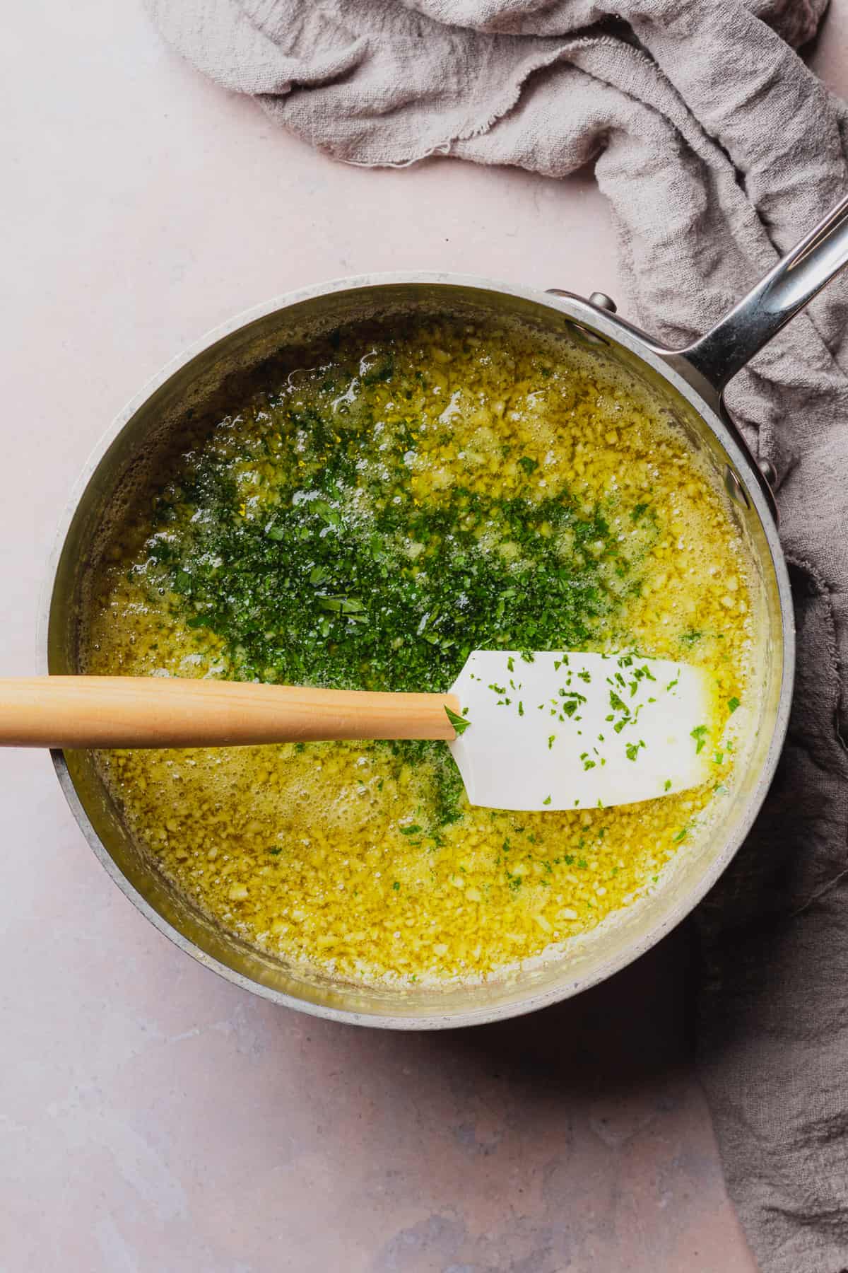 butter, garlic, and parsley in a pan with a rubber spatula.