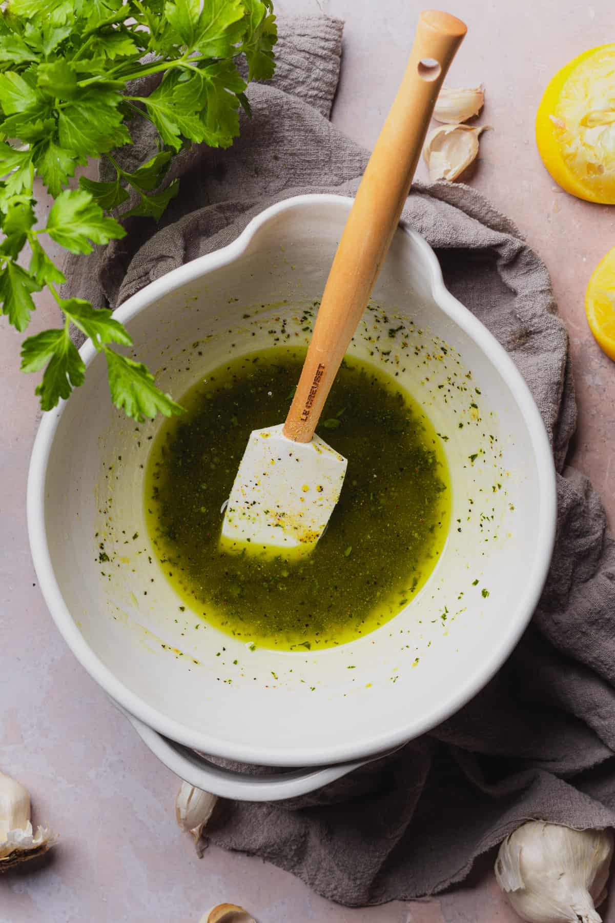 buttery garlic sauce with parsley in a bowl with fresh lemon juice and rubber spatula. 