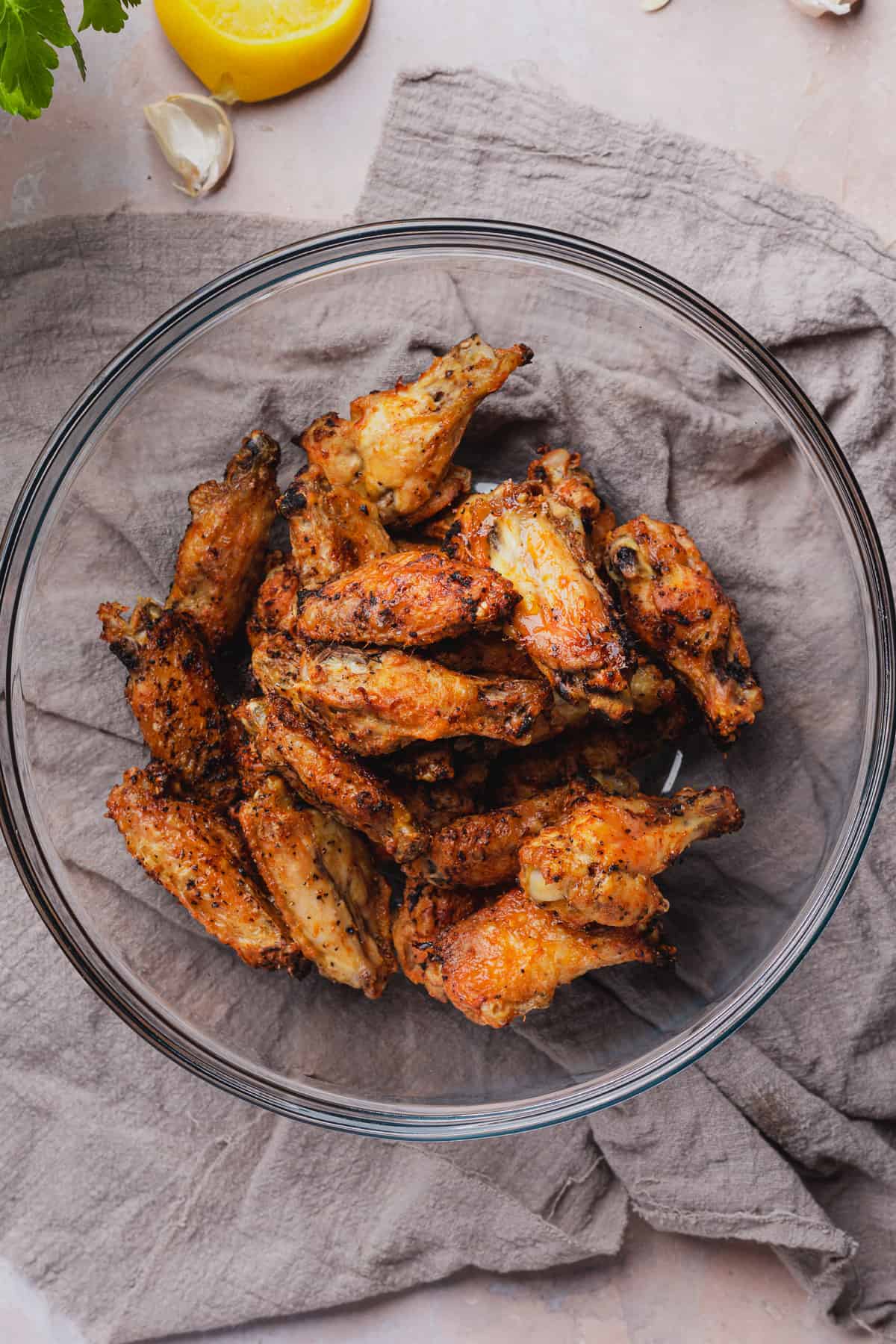 crispy cooked chicken wings in a large glass mixing bowl. 