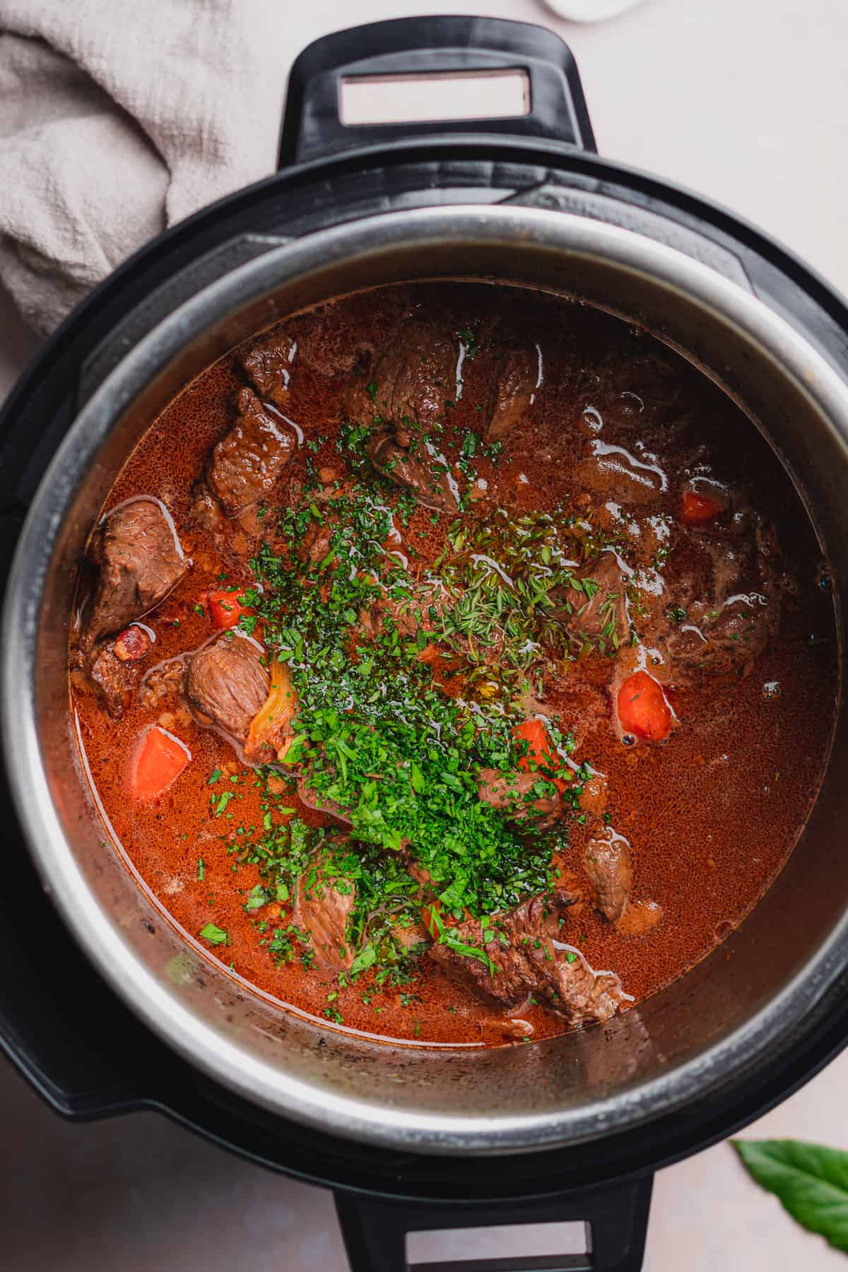 pressure cooker beef bourguignon with beef stock, red wine, parsley, and thyme in an Instant pot. 
