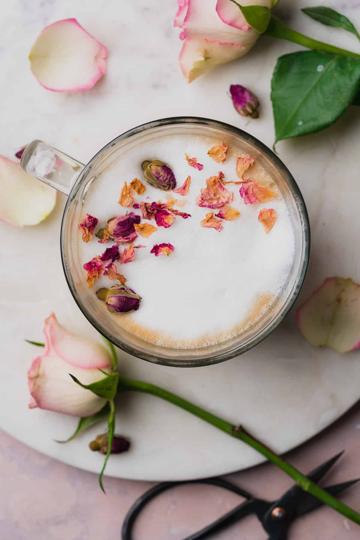 overhead view of a rose latte with edible rose petals and real roses. 