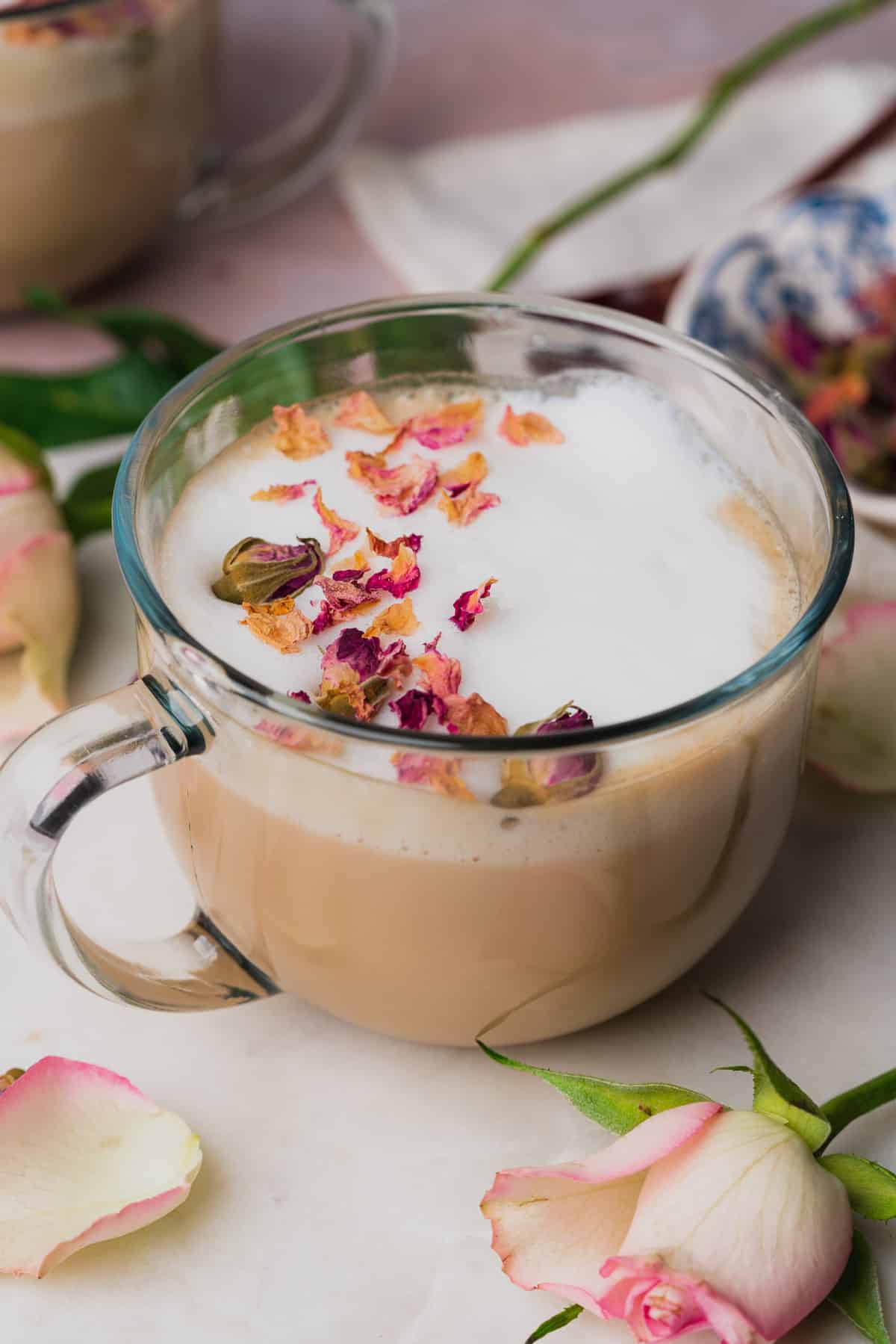 beautiful rose latte in a large glass mug, topped with rose petals. 