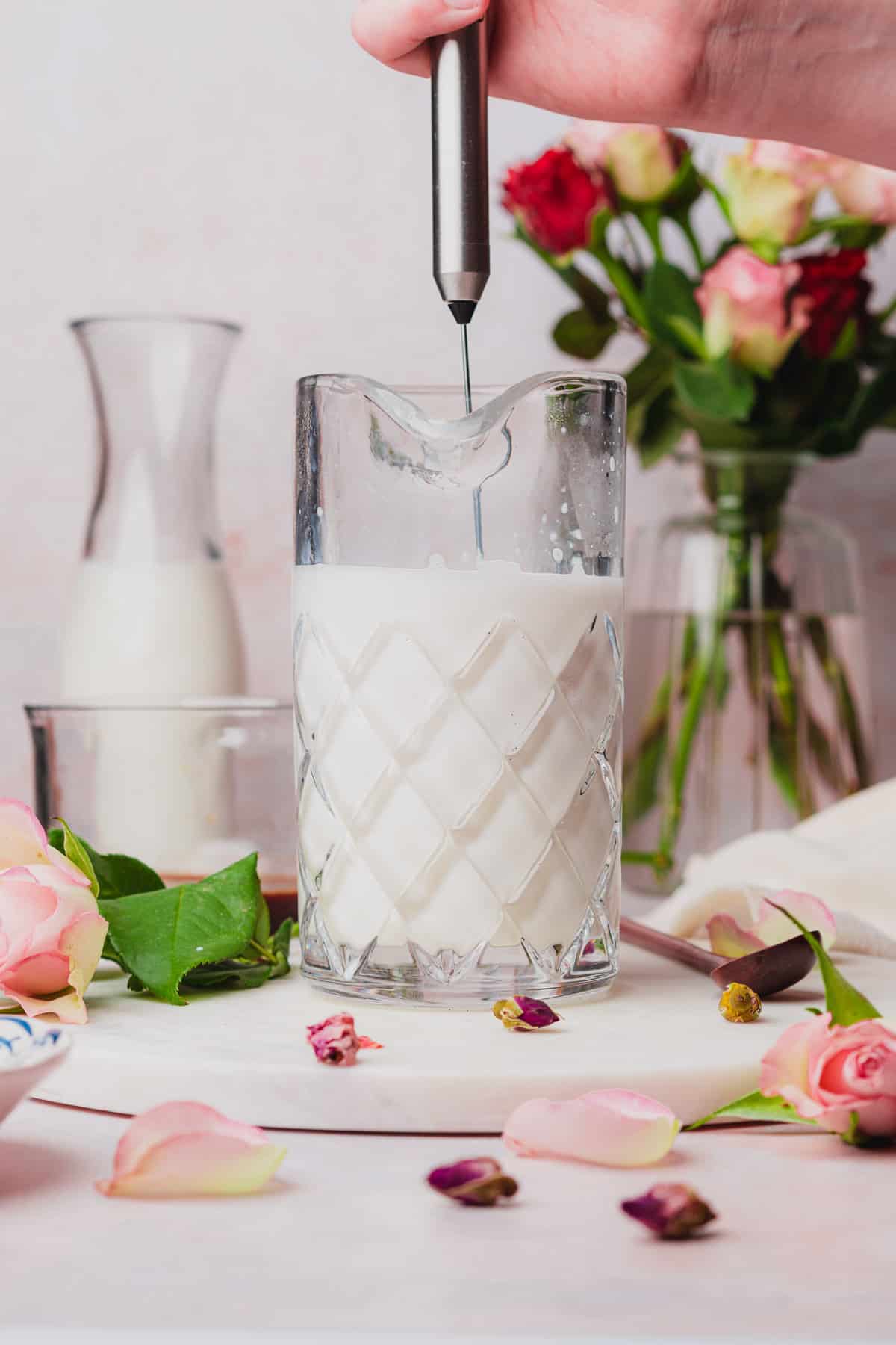 frothing milk in a container surrounded by roses. 