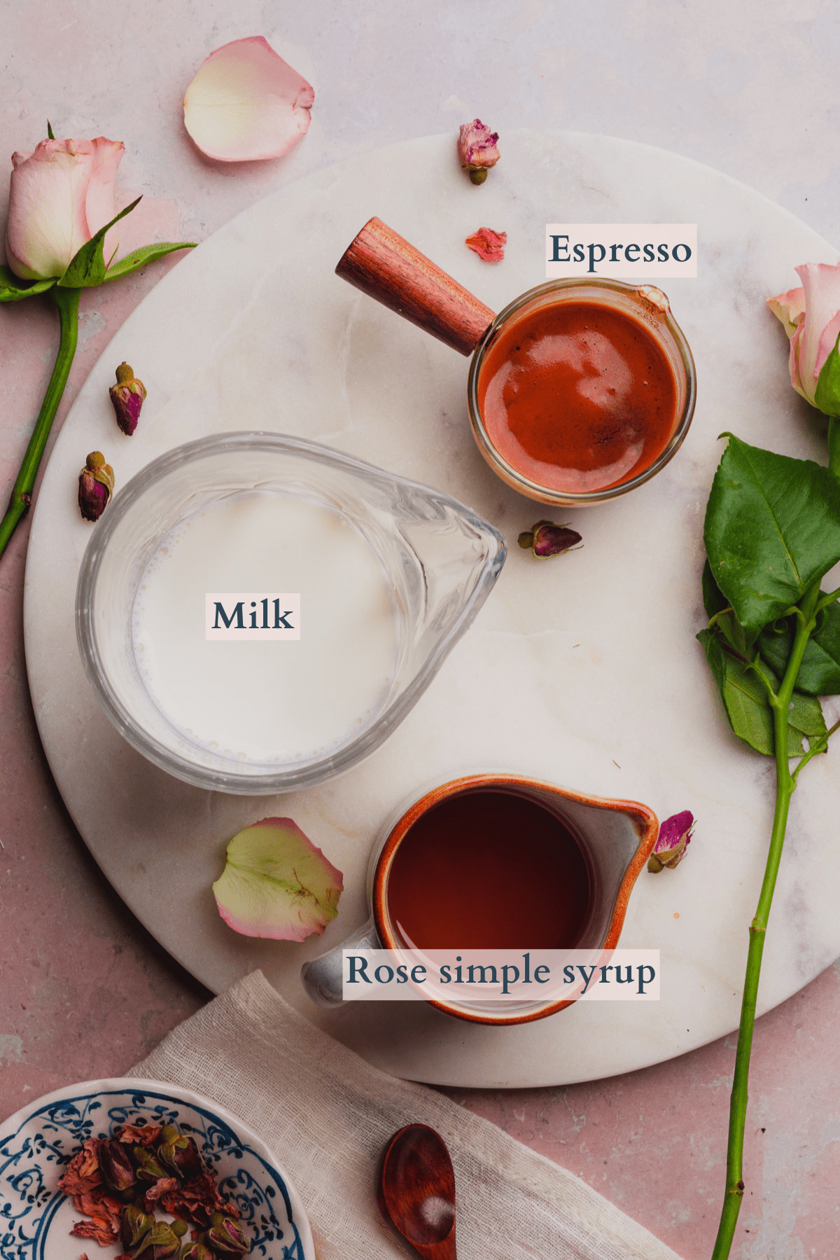 rose latte ingredients graphic with milk, espresso, rose simple syrup and edible rose petals, and text to denote the ingredients.