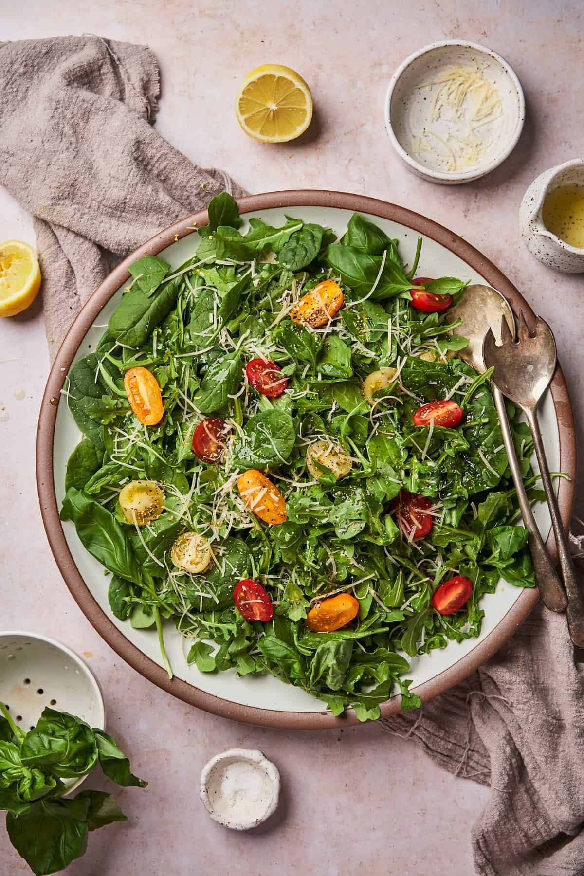 large platter with an arugula spinach salad with tomatoes, parmesan and lemon. 