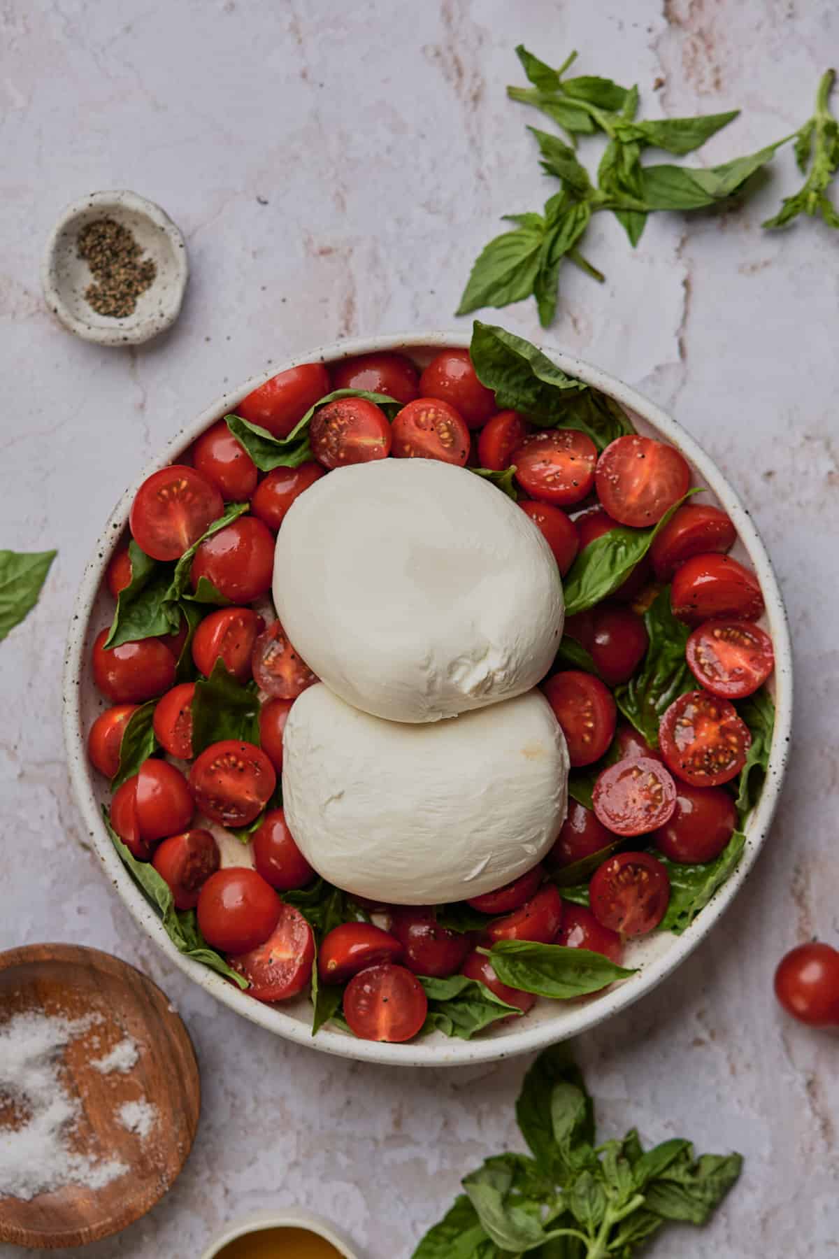 two large burrata balls on top of a bed of tomatoes and basil. 