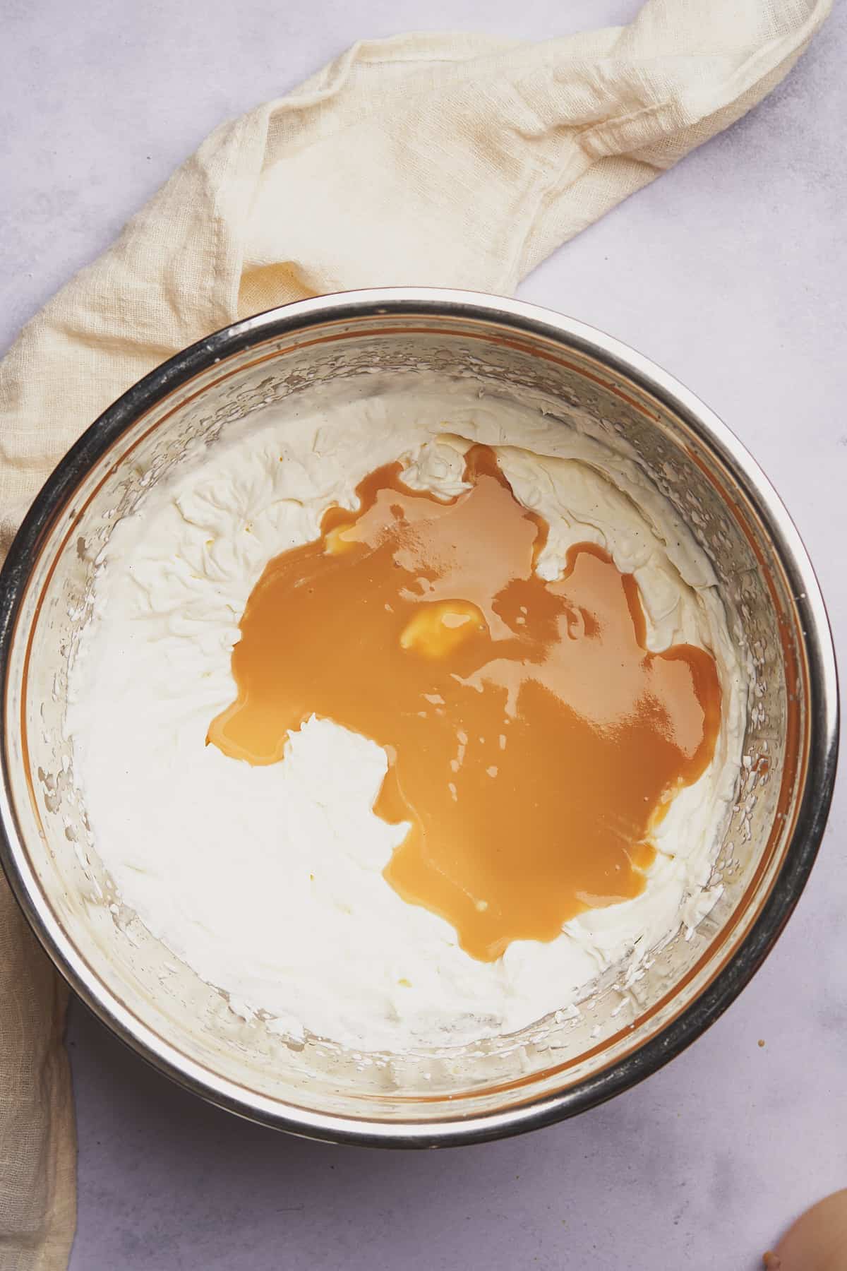 sweetened condensed milk added to the whipped cream in a bowl. 
