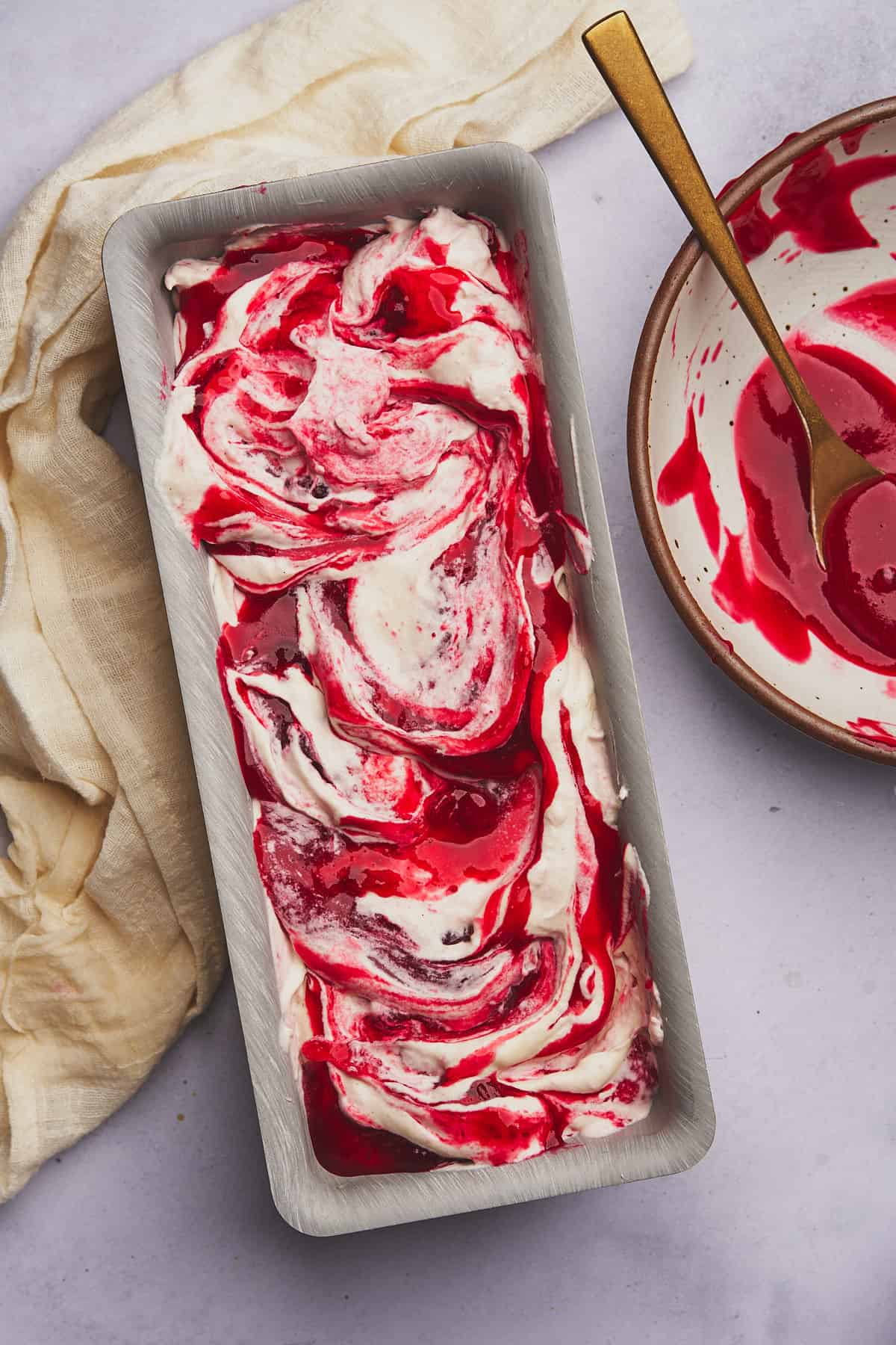 swirled cranberry sauce into ice cream in a loaf pan getting ready for the freezer. 