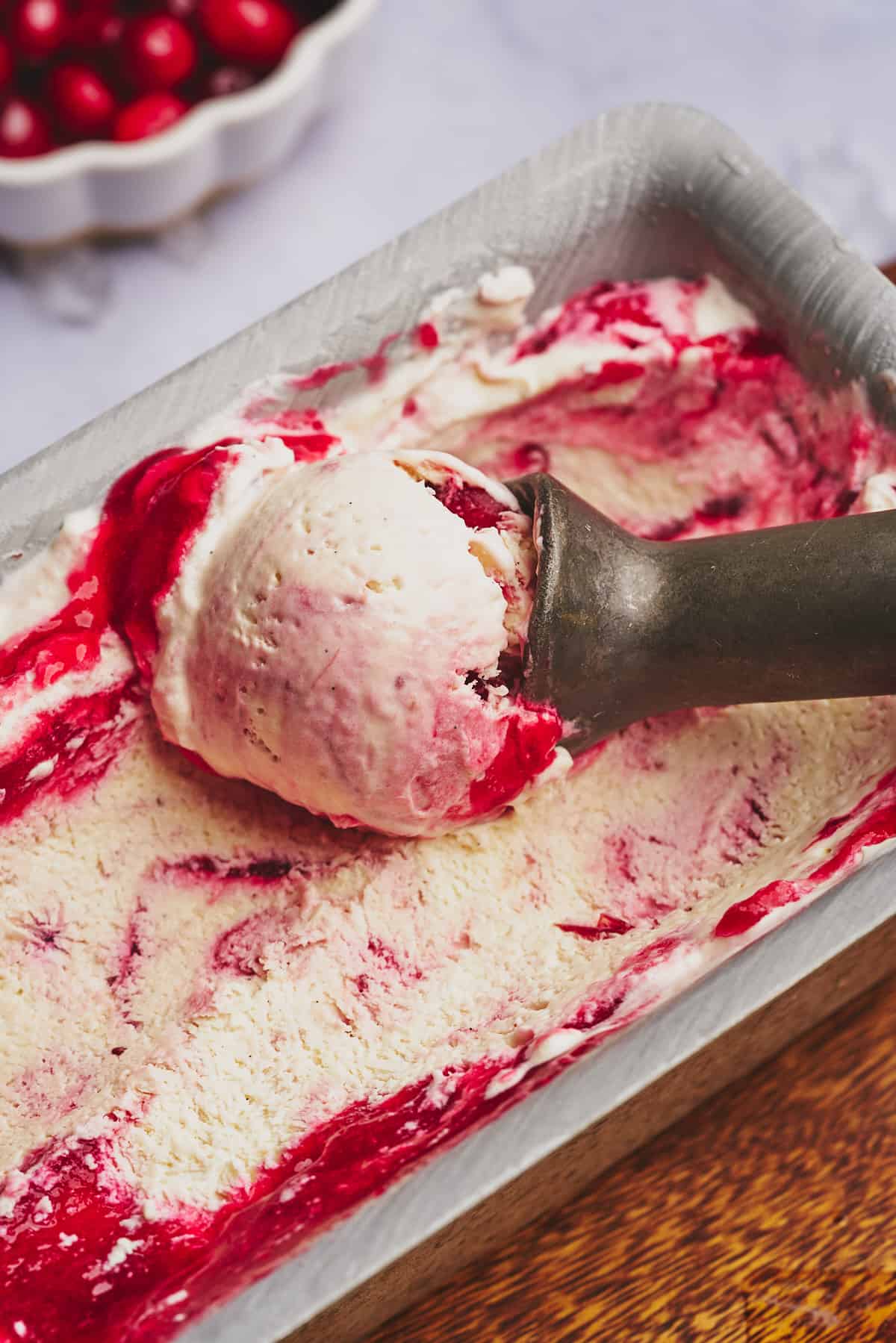 ice cream scoop full of cranberry ice cream in a loaf pan. 