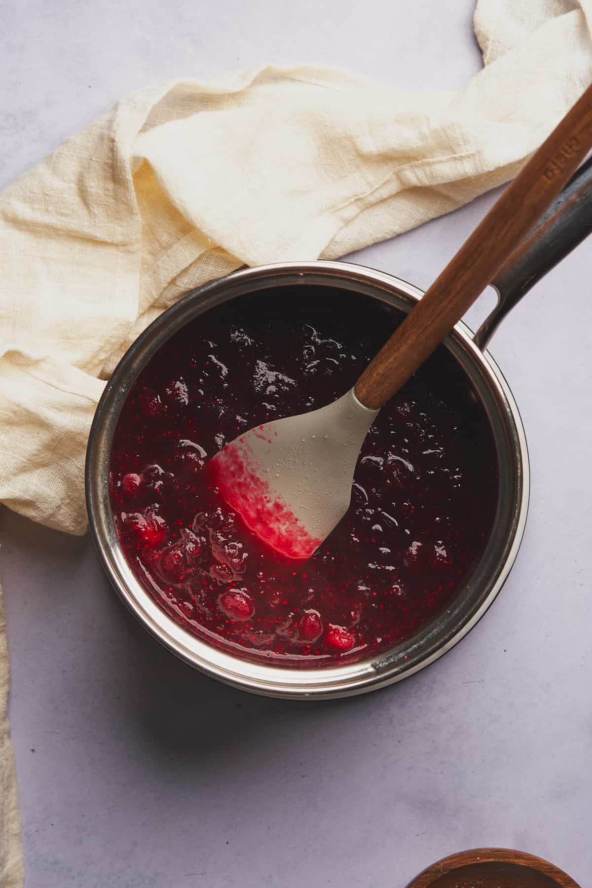 cranberry sauce in a saucepan with a rubber spatula, beginning to turn into a sauce. 