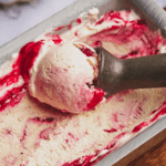 cranberry ice cream being scooped with a silver metal ice cream scoop.