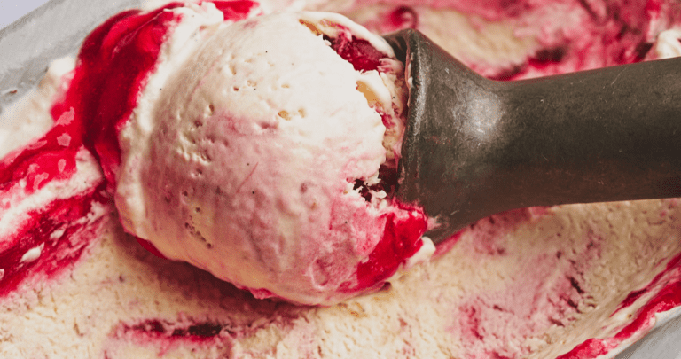 cranberry ice cream being scooped with a silver metal ice cream scoop.