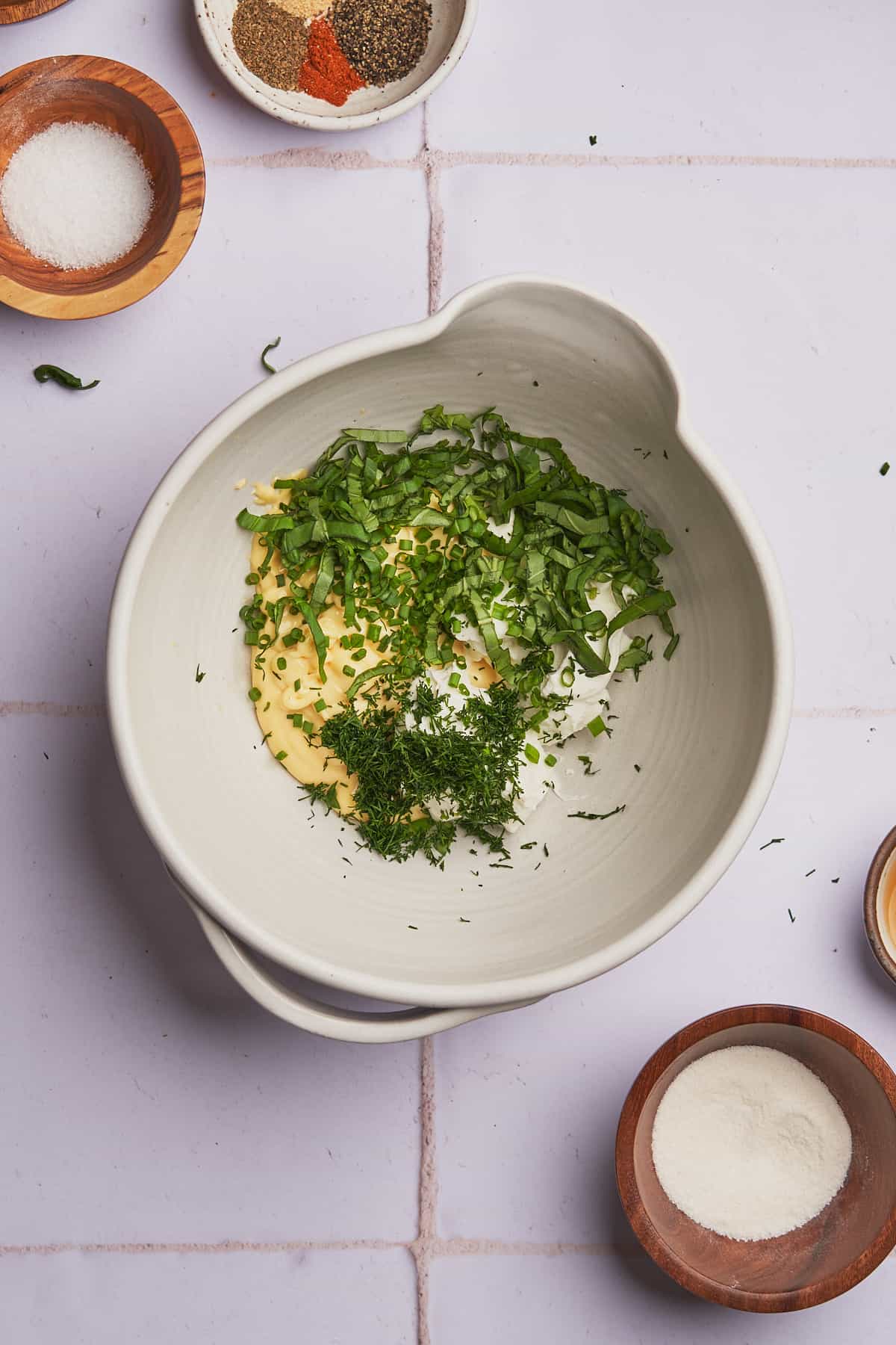 herbs, mayonnaise, and sour cream in a mixing bowl. 