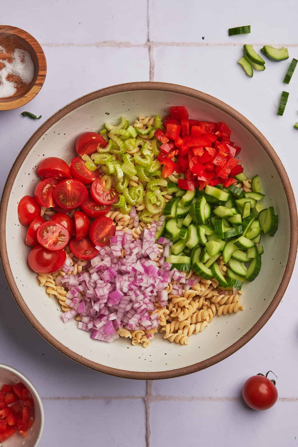 cooked pasta with tomatoes, cucumbers, red onion, celery, and red bell peppers.