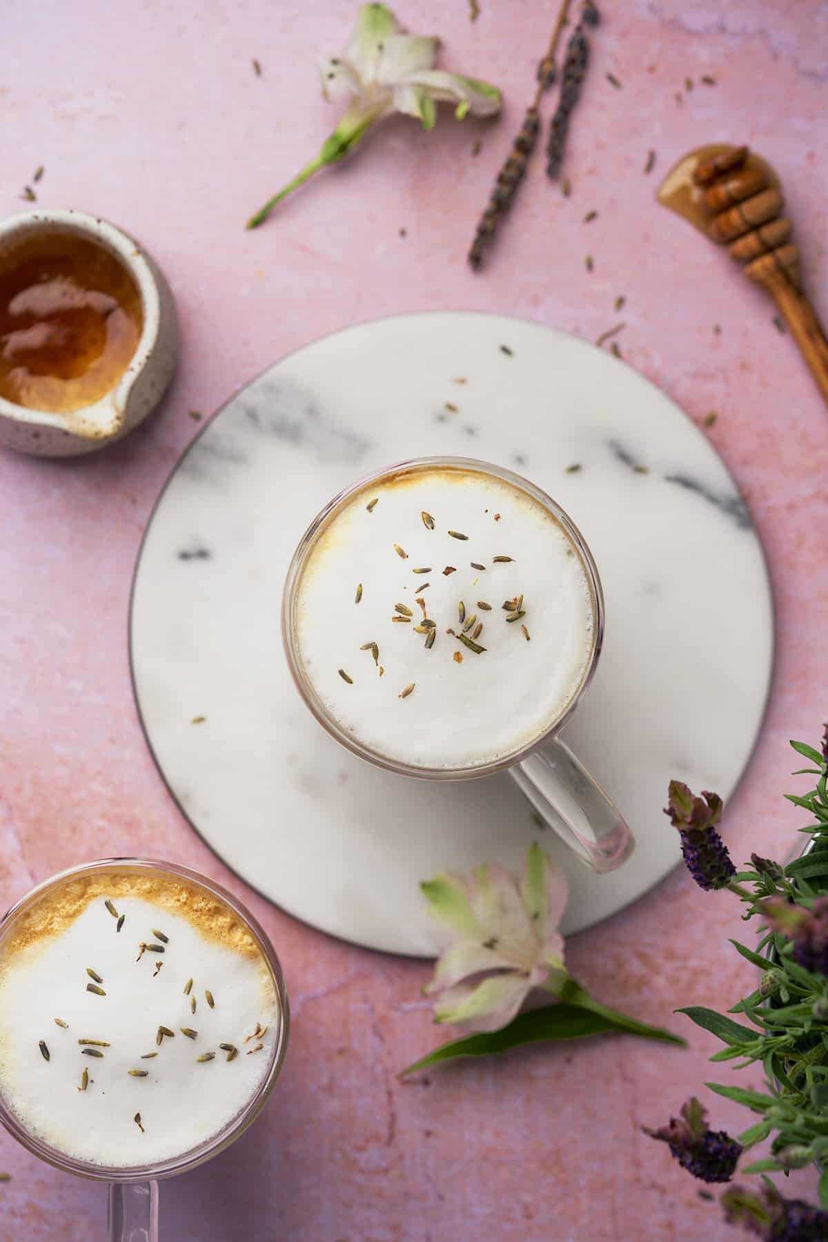 very pretty flat lay of two honey lavender lattes with dried lavender buds on top. 