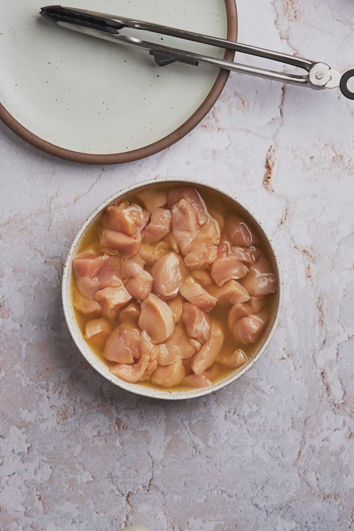 raw chicken pieces in a bowl of pickle brine. 