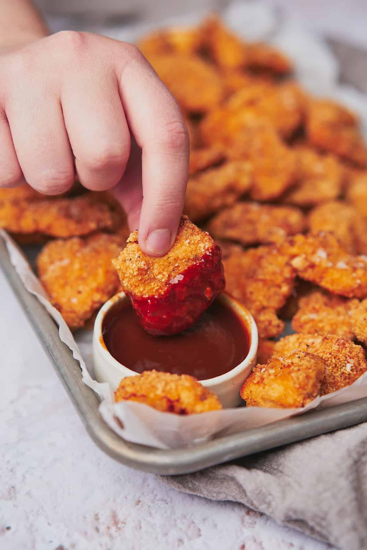 hand dunking keto chicken nuggets into bbq sauce. 