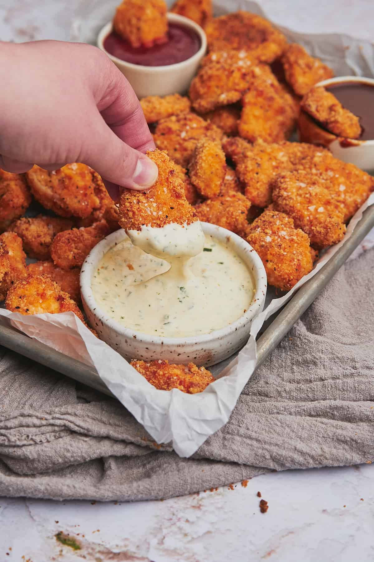hand dipping keto chicken nuggets in ranch. 