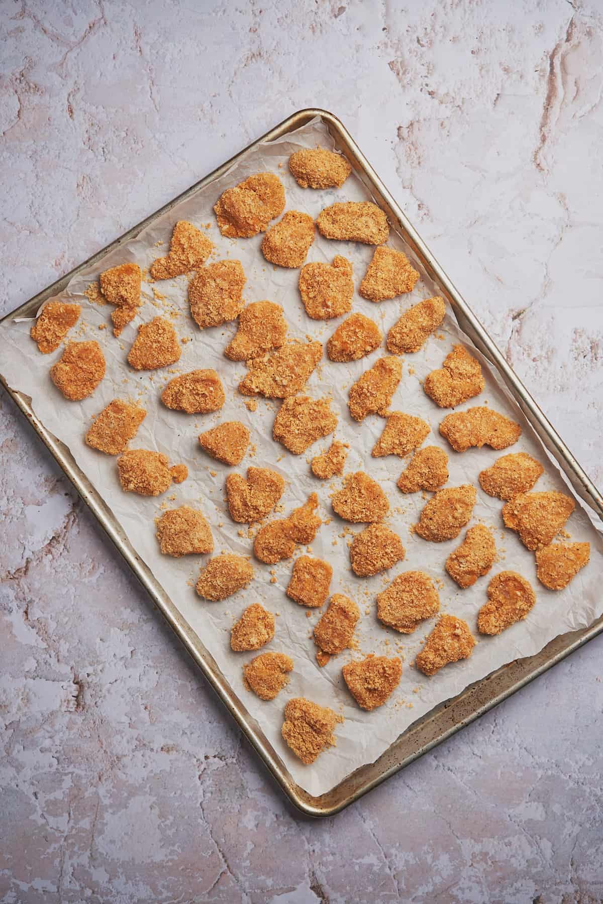 baking sheet full of raw keto chicken nuggets about to be baked. 