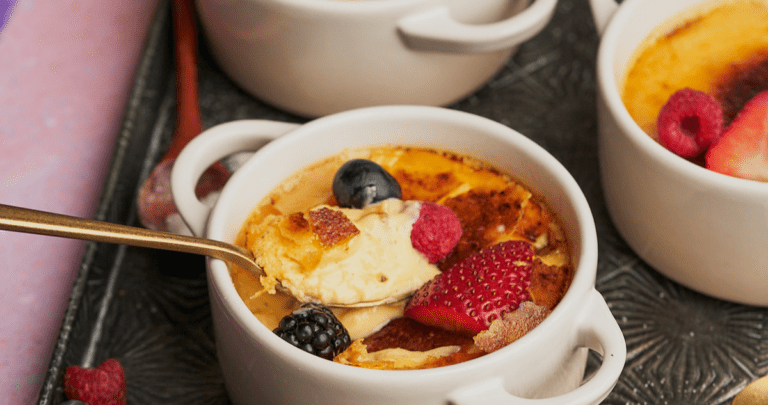 keto creme brulee recipe topped with berries and a spoon broken inside