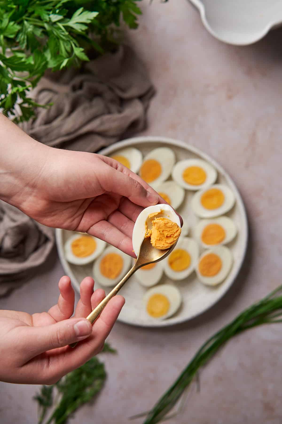 hand using a small spoon to remove the hard boiled yolk from the egg white. 