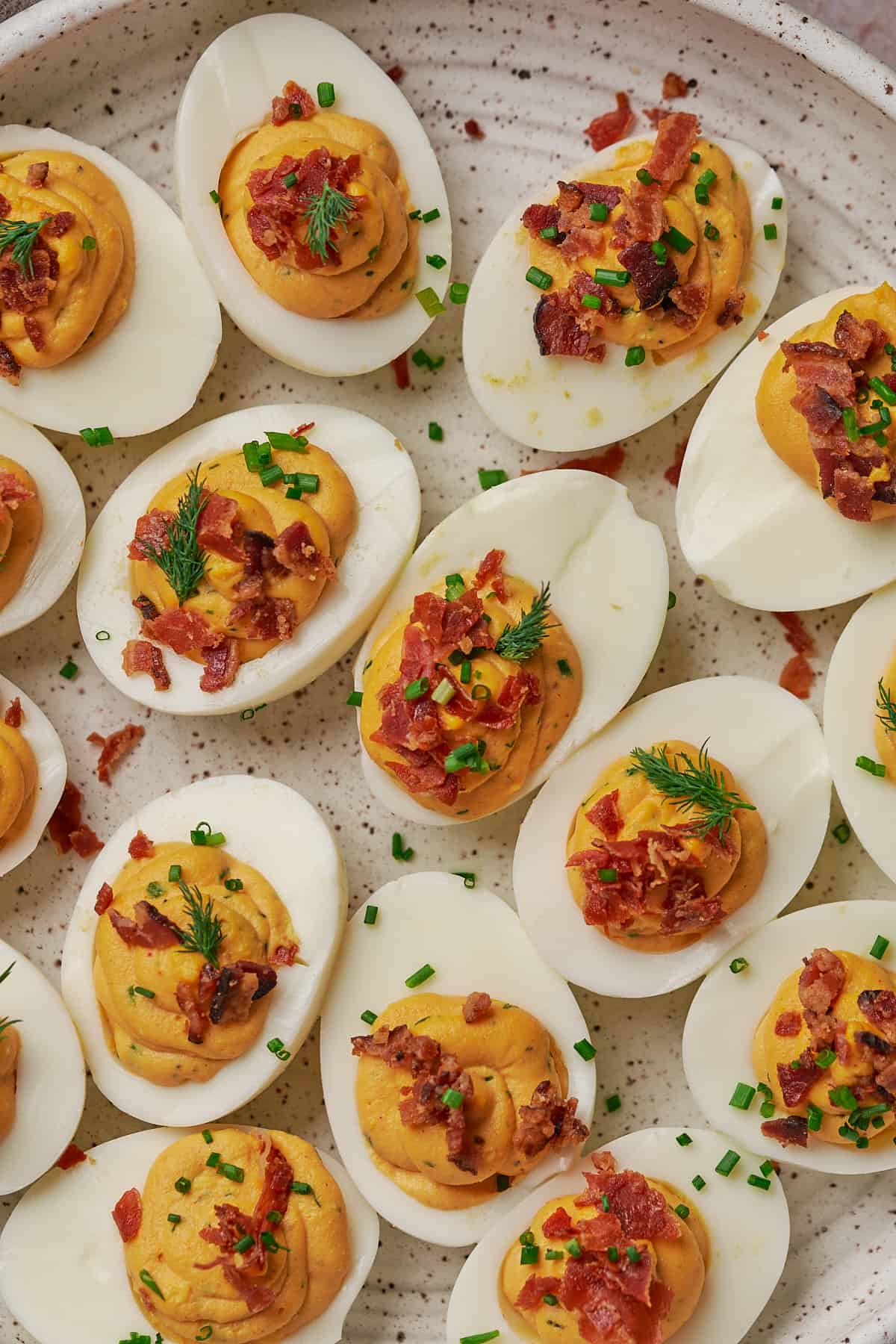 close up shot of keto deviled eggs with bacon, prosciutto, chives, and dill. 
