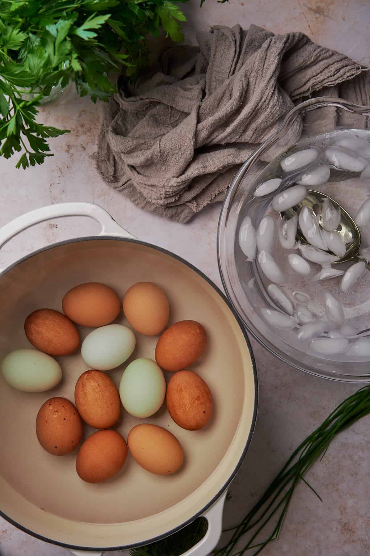 blue and brown eggs in a pot of water, next to an ice bath. 