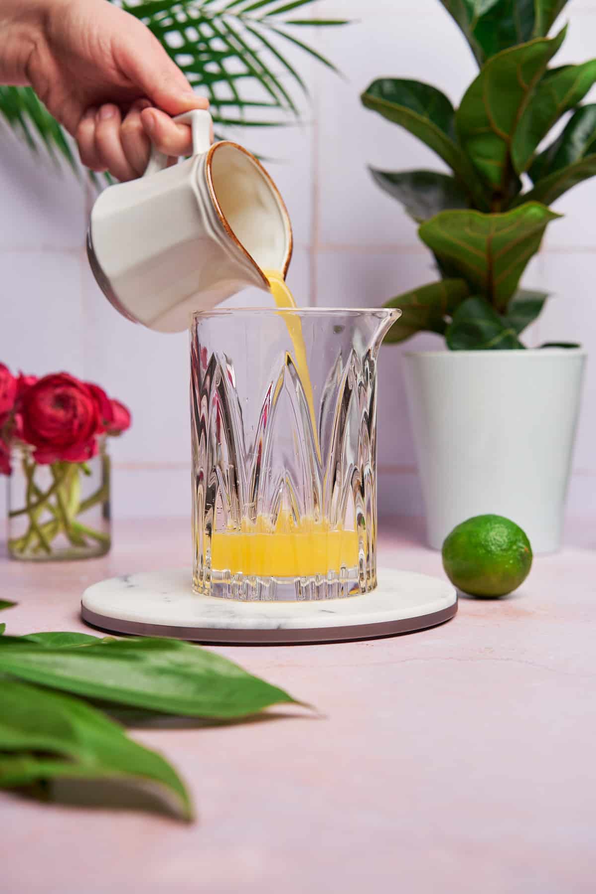adding pineapple juice to a mixing glass. 