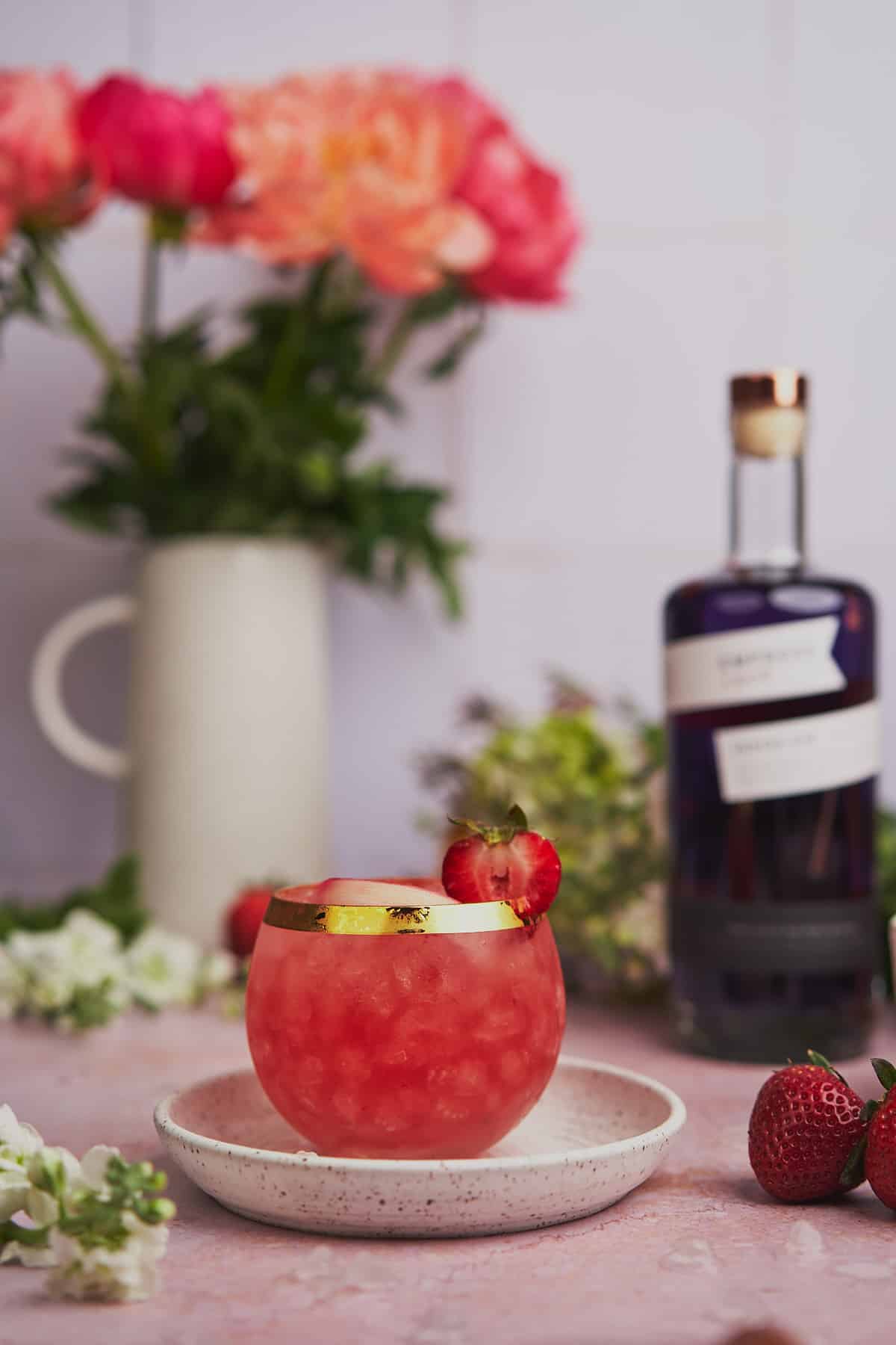 stunning rhubarb gin cocktail, with flowers in the background, along with Empress 1908 gin. 