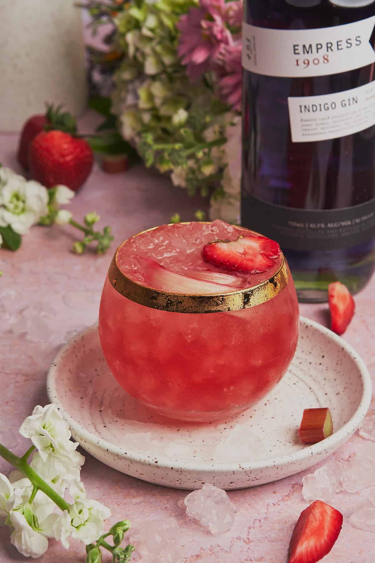 stunning shot of a rhubarb gin cocktail with strawberries and empress 1908 gin. 