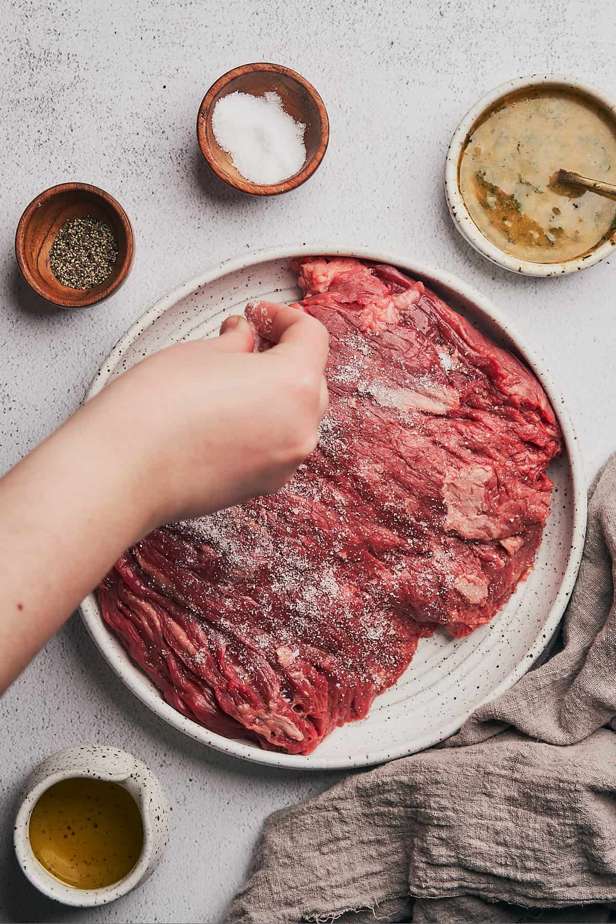 hand seasoning bavette steak very well with salt.
