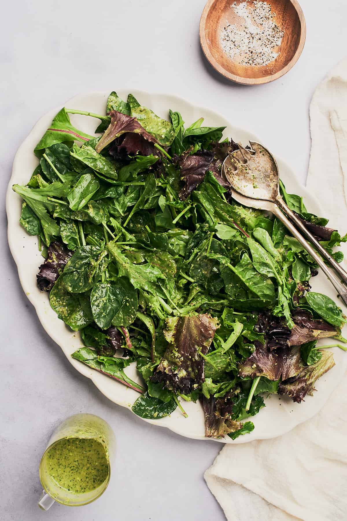 leafy greens dressed with a little salt and pepper on a large serving platter. 