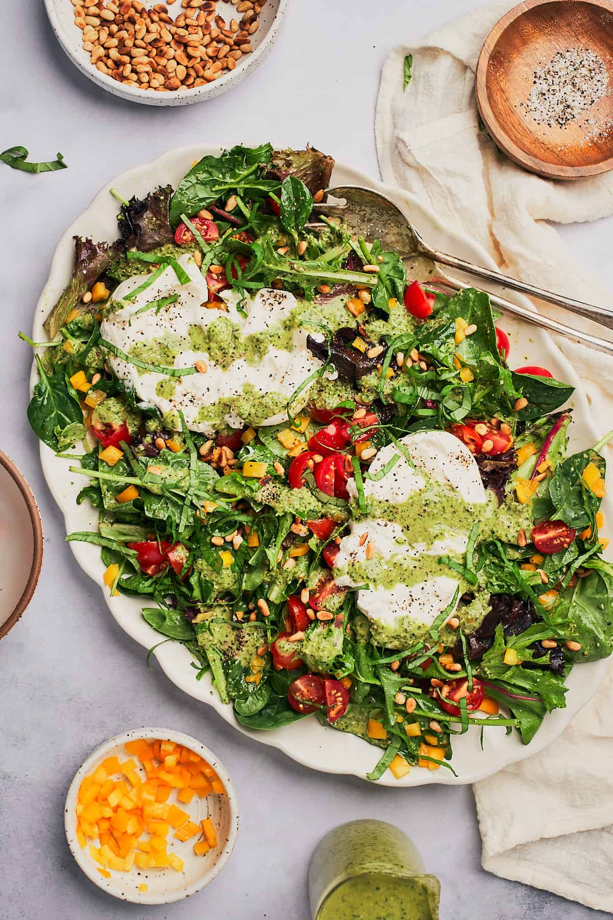 Burrata salad topped with pesto vinaigrette, toasted pine nuts, cherry tomatoes, and yellow bell peppers. 